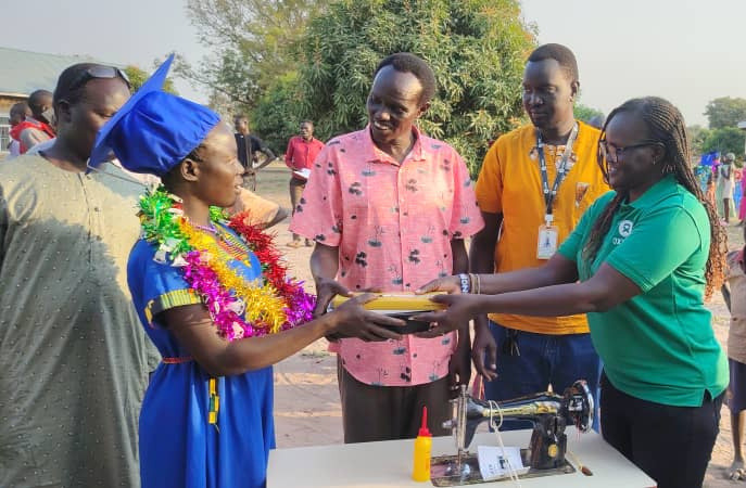 A vocational training graduate in academic dress receiving a gift at a Building Resilience ceremony